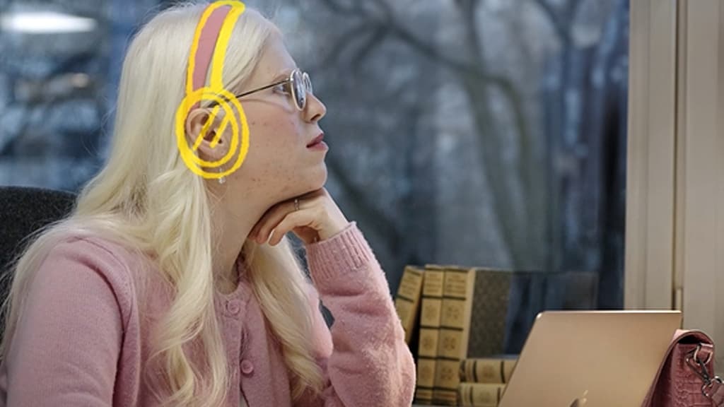 Nora sitter foran en MAC og lytter. Et headset i gult er tegnet på henne.